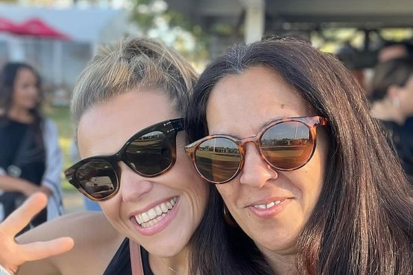 Two smiling friends in sunglasses squeeze into a selfie on a sunny afternoon