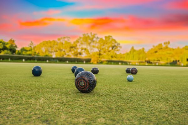 Black barefoot bowls scattered in an open green field