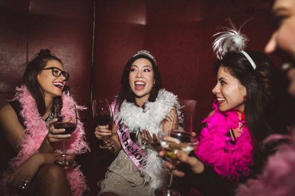 Friends in a nightclub booth at a hens with pink outfits