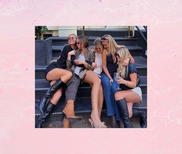Friends in boots laughing together on city steps with a glass of wine