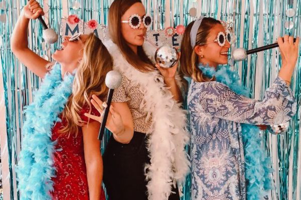 Three friends with feather boas, microphones and disco balls against blue tinsel