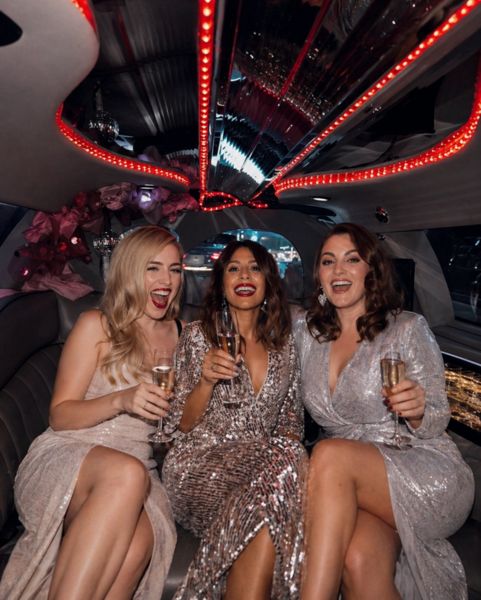 hens squad enjoing sparkling wine inside limousine
