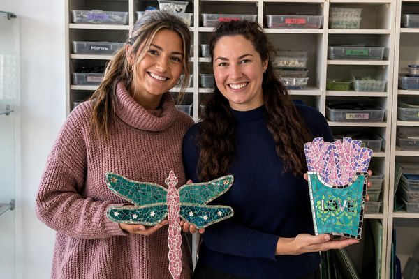 Two friends smiling with their finished dragonfly mosaic and flower pot mosaic