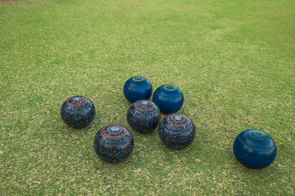 Balls for barefoot bowling are scattered across a lush field and ready to play