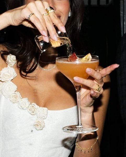 A woman in a white floral dress holding a garnished cocktail