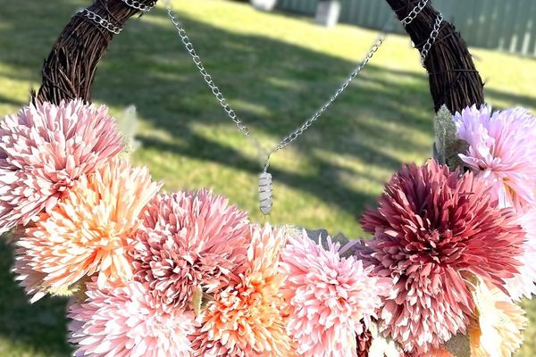 A crescent moon wreath of pink and peach flowers with a hanging crystal