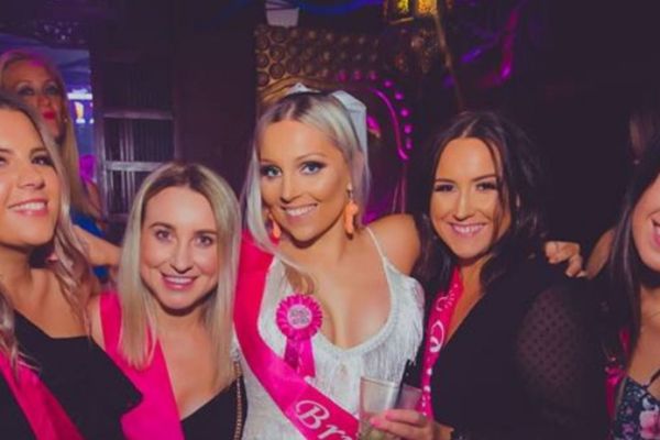 A bride to be in a pink sash and rosette with friends on a night out
