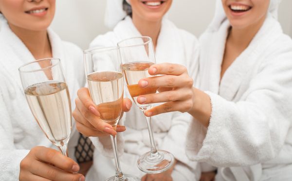 Friends in white robes clinking flutes of bubbly