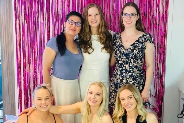 A group of friends in fresh glam in front of pink tinsel