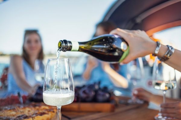 Bubbles being poured into a glass at a sunny table on a boat