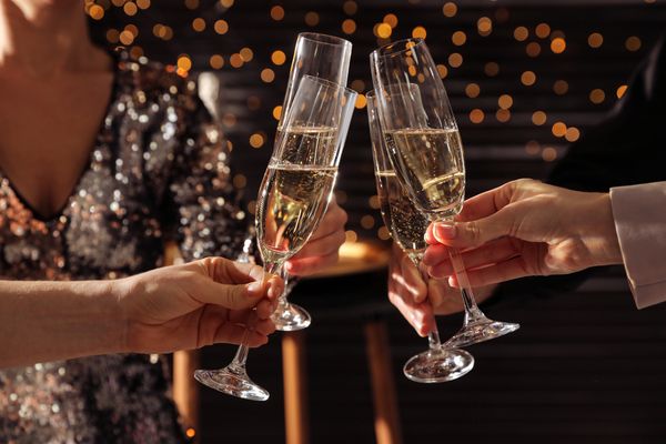 Three women dressed fabulously clinking glasses of champagne