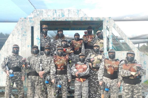 Paintball squad in camo overalls and full face masks lined up at the arena