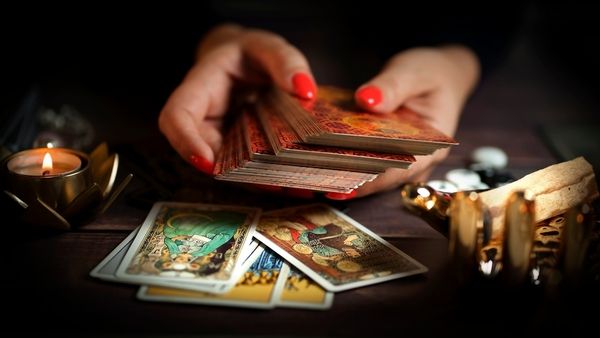 Hands with red nails laying out tarot cards by candlelight