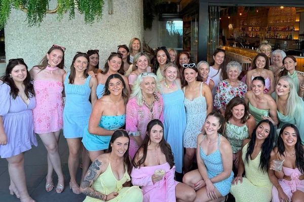 Big hens group of all ages in pastel dresses gathered together outside a bar