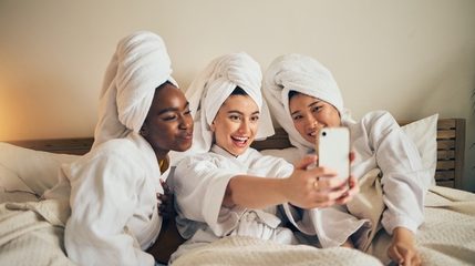 Four friends in robes and towel turbans laughing at a day spa