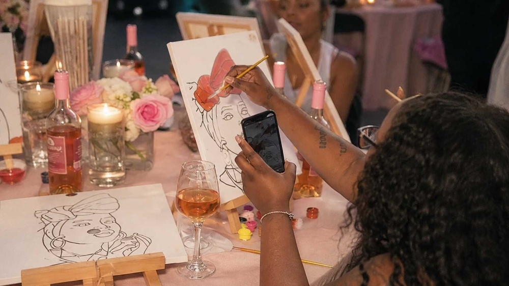 Women sketching at a table with flowers and drinks