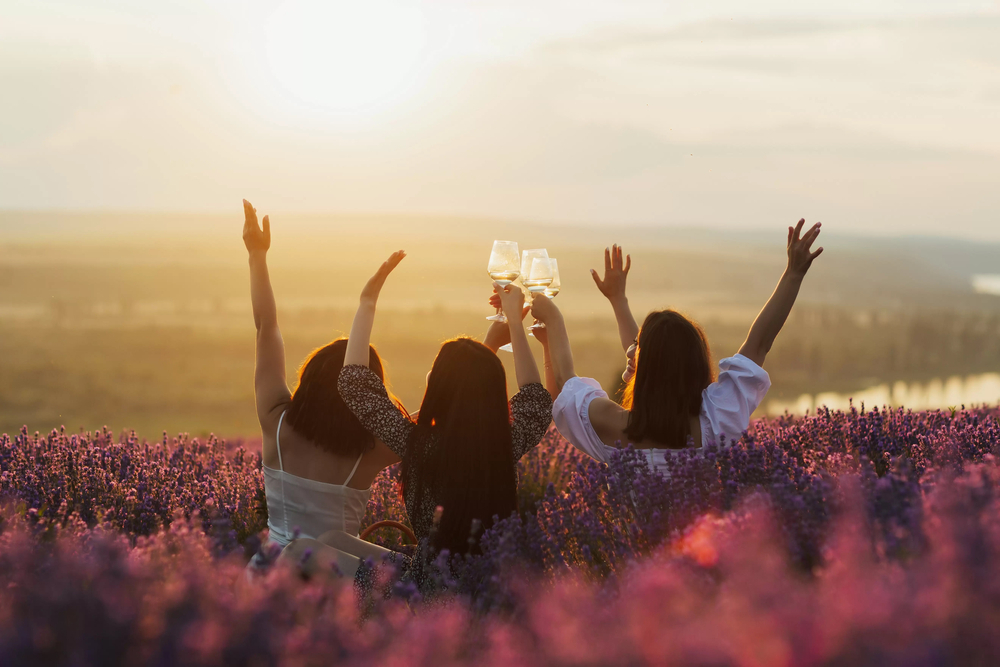 A hens crew throwing their arms up together on the lawn outside a winery