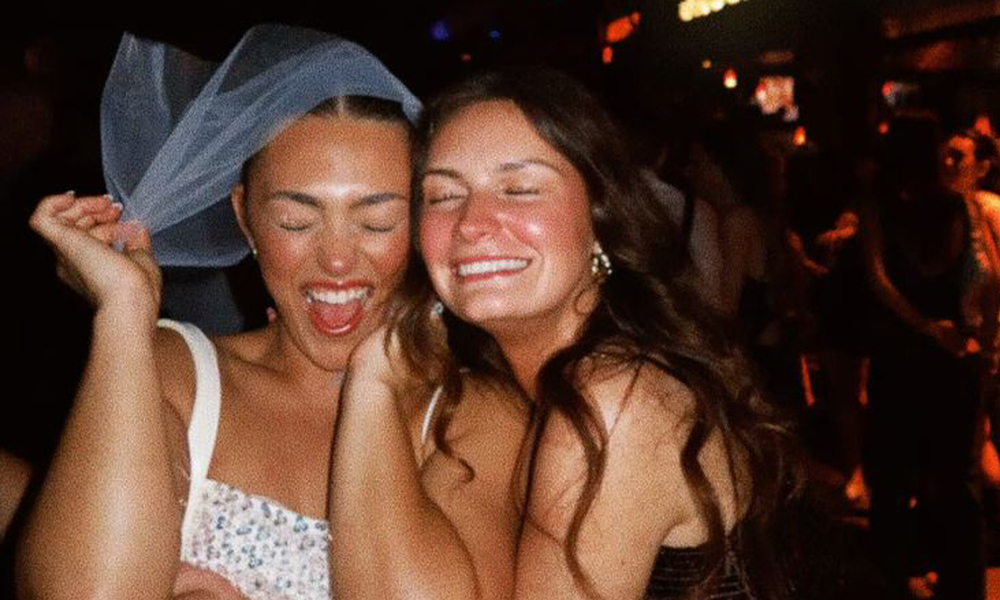 The bride in her veil hugging a friend and laughing