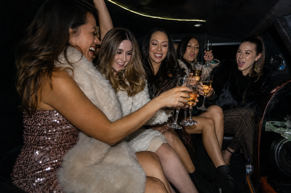 A group of women toasting drinks inside a limousine
