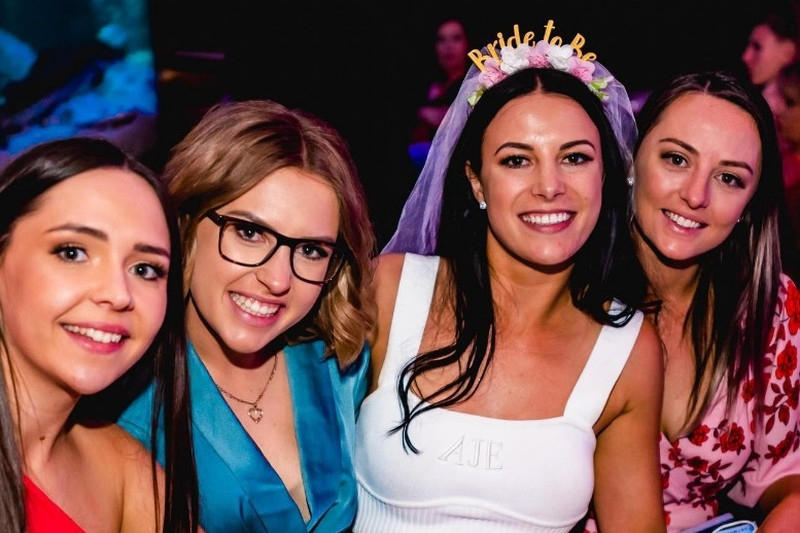 The bride in a veil headband smiling with three friends at night