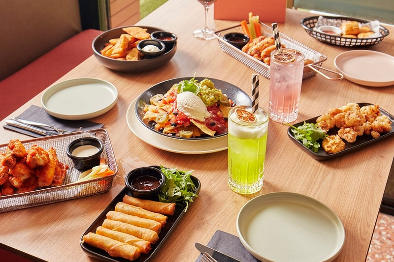A table of share plates, spring rolls and colourful cocktails