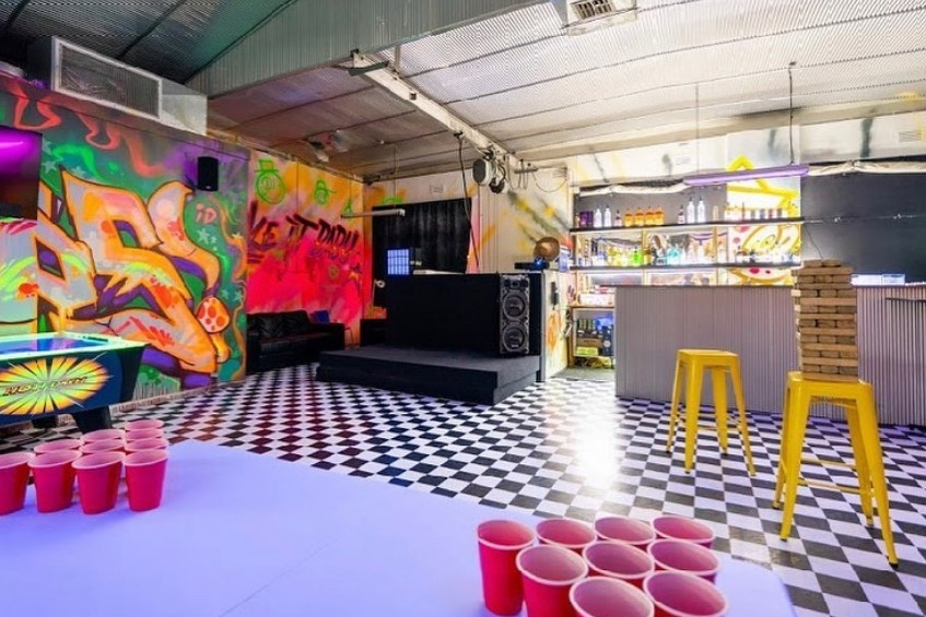 A beer pong table set with red cups in a colourful checkered games room
