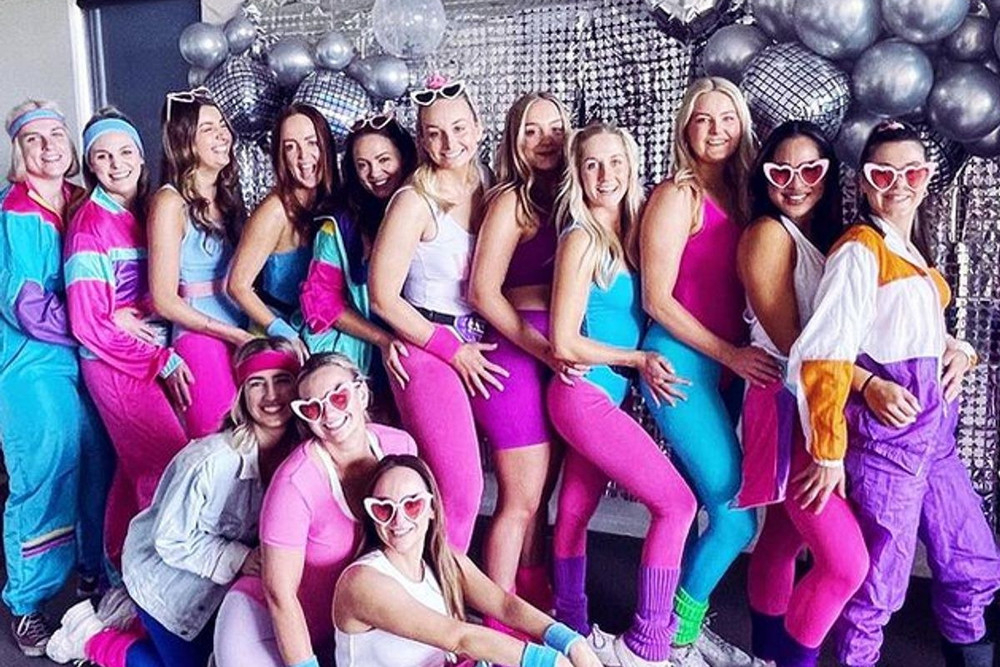 A hens group in bright retro tracksuits and heart sunglasses