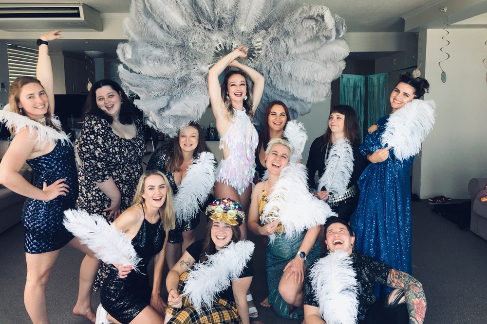 A hens group posing with white feather fans at a burlesque class