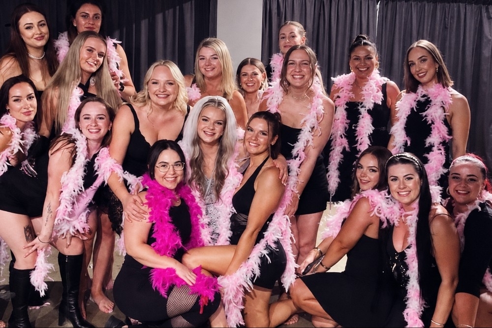 A big hens group in black dresses and pink feather boas after a burlesque class