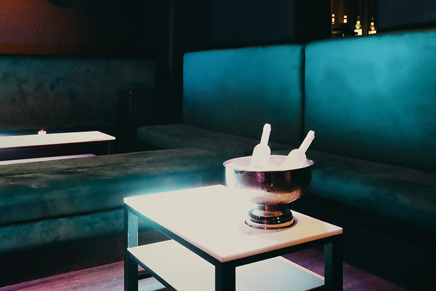 A teal velvet booth with a bottle of bubbly on ice