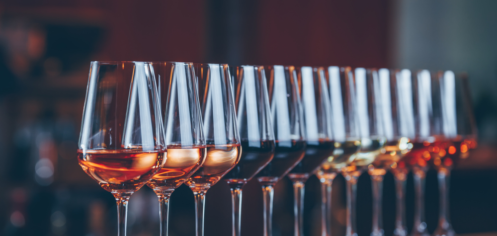 A long row of wine glasses lined up for a tasting, catching warm light
