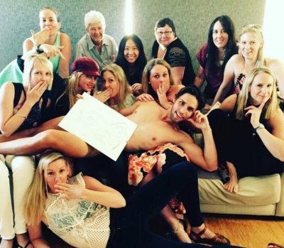 Lauren's group on a couch with a shirtless man, holding up their drawings
