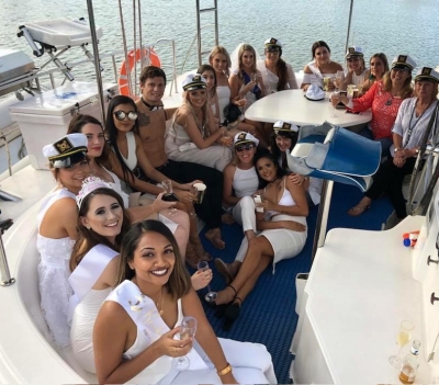 Samantha's hens crew seated on the deck of their boat on the sunset cruise, one friend in a sash