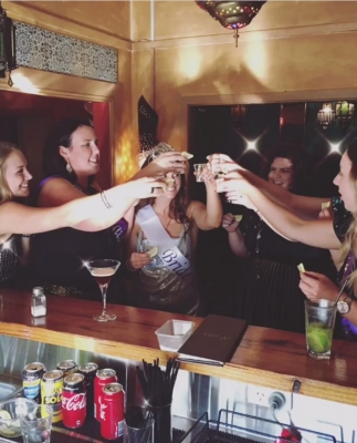 Jaime's hens group raising shot glasses at a bar
