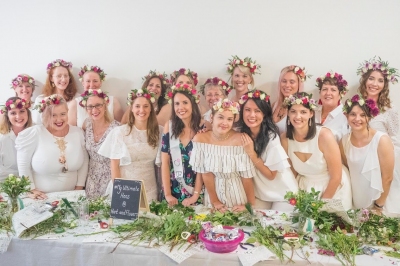A big hens group in flower crowns stands behind a table of greenery, from the reviewer’s own photo