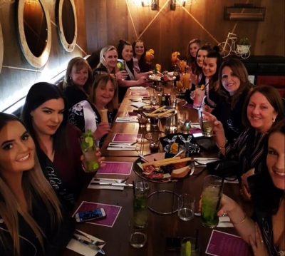 The hens group around a long dinner table after their cocktail class
