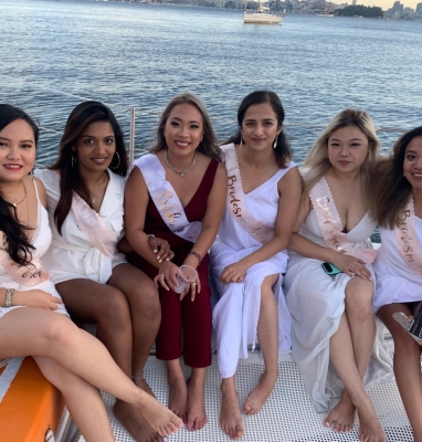 Cynthia's hens crew in white sitting together on the deck of their boat