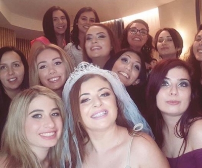 The bride in a tiara and veil taking a selfie with her hens